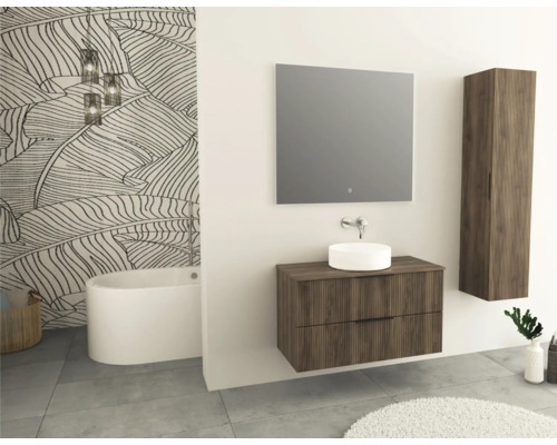 Salle de bains avec meuble-lavabo, miroir, armoire haute et baignoire devant un mur à motif de feuilles