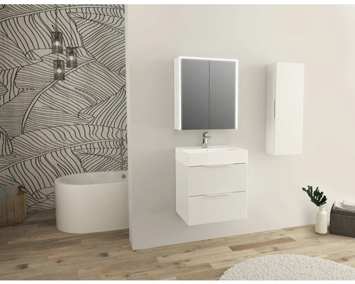 Helles Badezimmer mit Waschtisch, Spiegelschrank, Hängeschrank und Badewanne vor einer Wand mit Blättermuster.