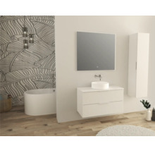 Salle de bains lumineuse avec meuble sous-lavabo, vasque à poser, miroir, armoire haute et baignoire devant un mur à motifs