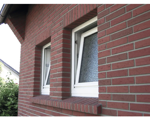 Aussenansicht eines Hauses mit zwei gekippten Fenstern und roter Backsteinfassade