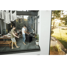 Des personnes font des grillades sur la terrasse avec un barbecue et des meubles de jardin