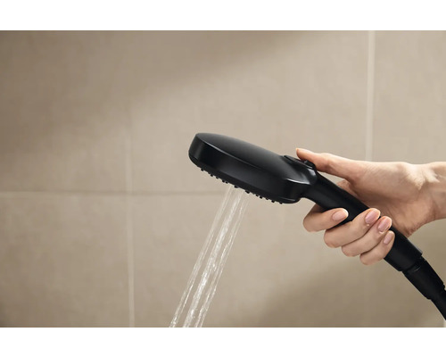 Main tenant une pomme de douche noire avec de l''eau qui coule