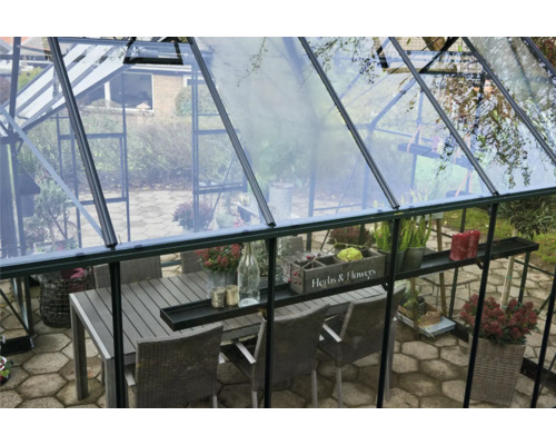 Gewächshaus mit Esstisch und Stühlen im Innenraum.
