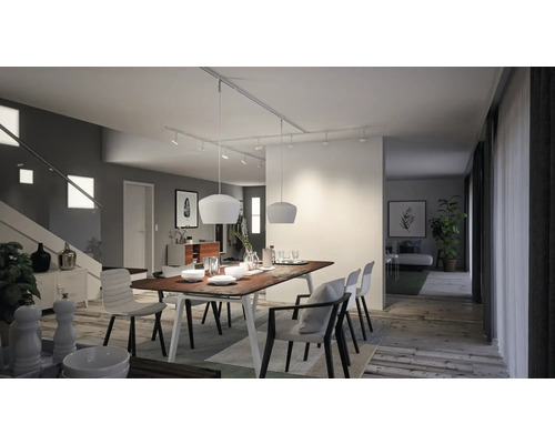 Salle à manger lumineuse avec table en bois, chaises et éclairage moderne.