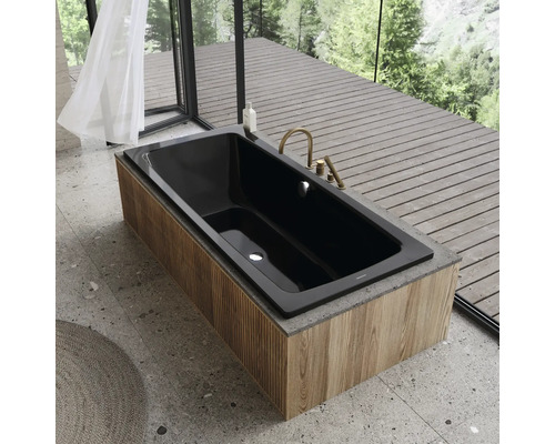 Baignoire noire avec habillage en bois et robinetterie dorée dans une salle de bains moderne.