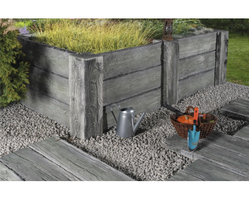 Jardinière surélevée en béton imitation bois, entourée de gravier et d''outils de jardinage