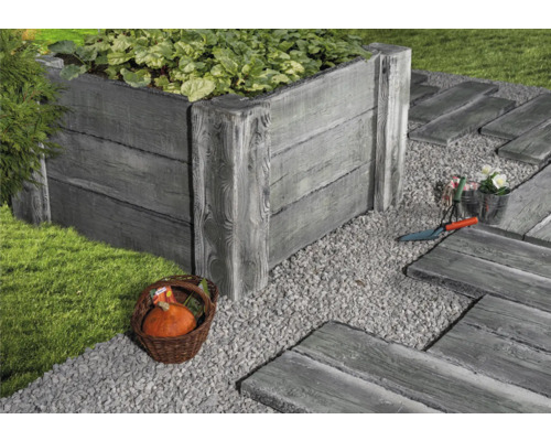 Scène de jardin avec potager surélevé, allée de gravier et décorations.