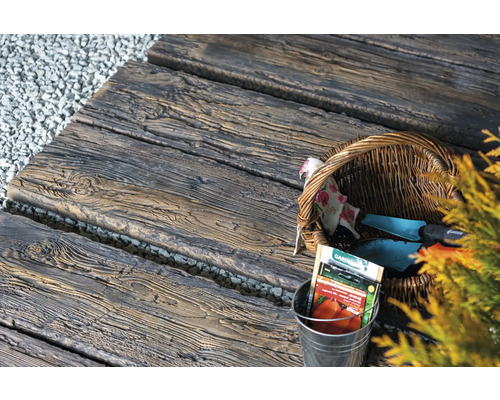 Gartenweg aus Betonplatten in Holzoptik mit Gartengeräten und Saatguttüten