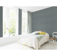 Chambre lumineuse avec lit, chaise et mur gris