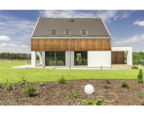 Maison moderne avec éléments en bois, fenêtres de toit et jardin soigné