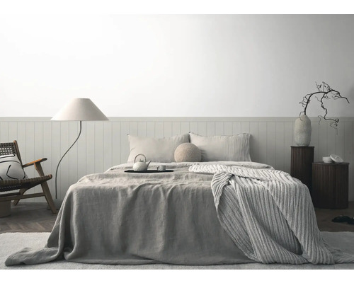 Helles Schlafzimmer mit Bett, Nachttischen, Stehlampe und Sessel