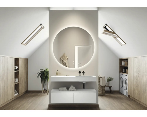Helles Badezimmer im Dachgeschoss mit Waschtisch, rundem Spiegel mit Beleuchtung, Dachfenstern und Waschmaschine.