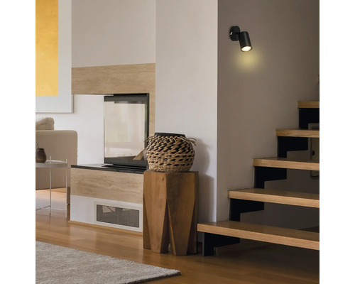 Salon avec escalier et applique murale LED noire montée au mur