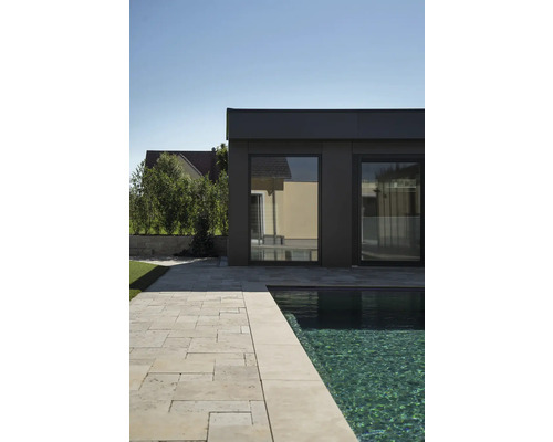 Vue extérieure d''une piscine moderne avec des dalles en travertin et un bâtiment