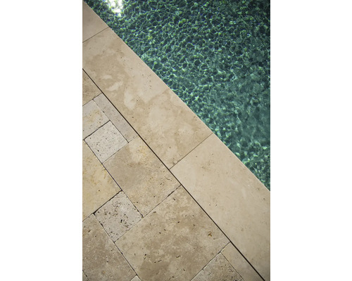 Vue détaillée des dalles de piscine en travertin au bord du bassin