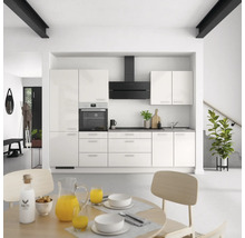 Cuisine claire avec armoires blanches, hotte noire et table à manger au premier plan.