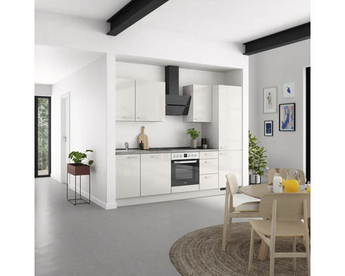 Cuisine moderne avec armoires blanches, hotte noire et table à manger en bois dans une pièce lumineuse.