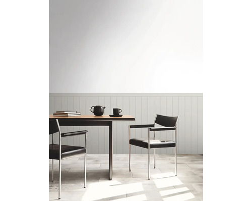 Esstisch mit Stühlen, Teekanne und Tasse in einem hellen Raum.