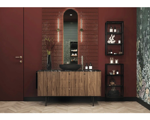 Badezimmer mit Waschtisch, Spiegel, Fliesen und Regalen für Badutensilien.