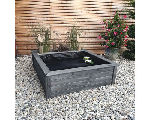 Quadratischer Teich aus Holz mit Wasserpflanzen und Dekoration im Garten