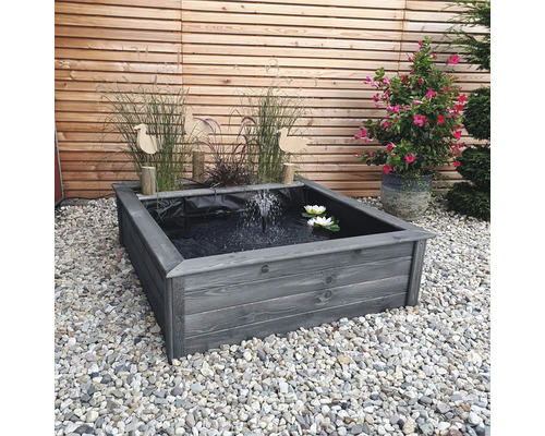 Bassin carré en bois avec jet d''eau et nénuphars dans le jardin.