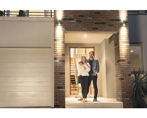 Maison moderne avec un couple devant la porte et éclairage extérieur