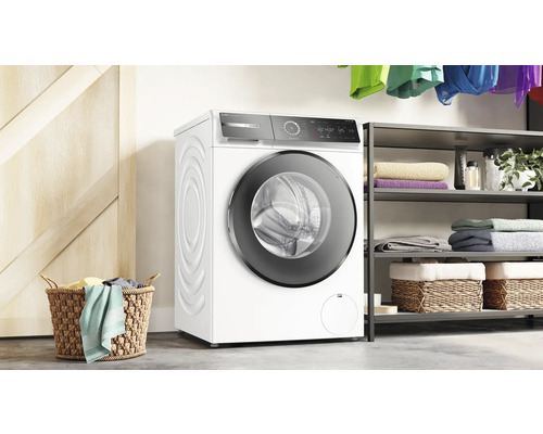 Machine à laver dans une buanderie lumineuse avec des étagères et un panier à linge