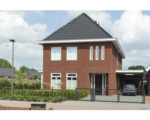 Freistehendes zweistöckiges Haus mit Ziegelfassade, dunklem Ziegeldach und Carport.