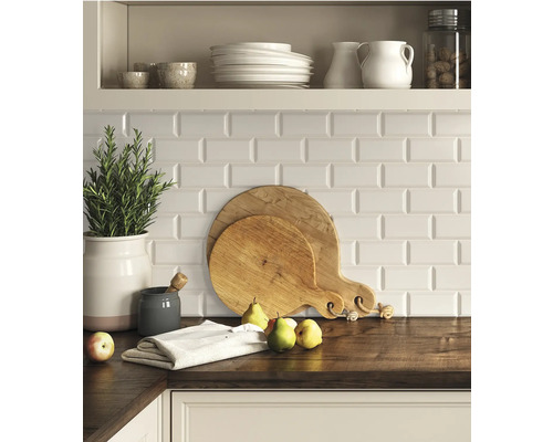 Küchenszene mit Schneidebrettern, Geschirr und Kräutern auf einer Arbeitsplatte vor einem Hintergrund mit weißen Fliesen.