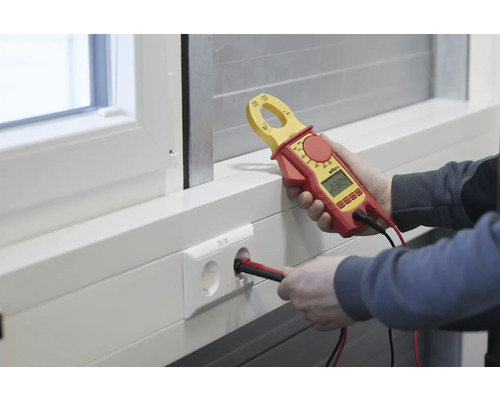 Électricien mesurant la tension d''une prise de courant avec un ampèremètre