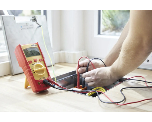 Elektriker misst Spannung mit einem Digitalmultimeter.