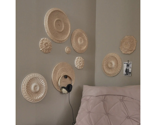 Décoration murale avec des rosaces en stuc et un support pour casque dans la chambre.