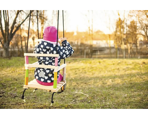 Enfant sur une balançoire en bois dans le jardin