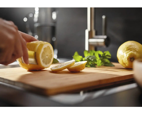 Eine Person schneidet eine Zitrone auf einem Schneidebrett in einer Küche.