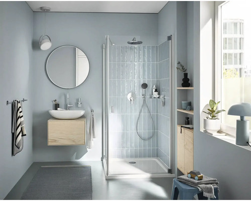 Salle de bains lumineuse avec douche, lavabo, miroir et serviettes