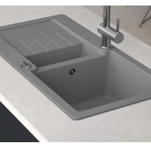 Graue Küchenspüle mit Abtropffläche und Armatur auf einer Küchentheke.