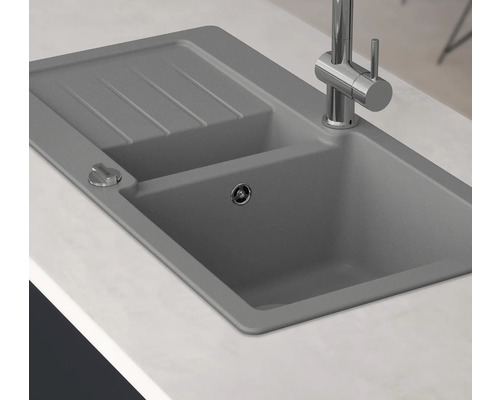 Graue Küchenspüle mit Abtropffläche und Armatur auf einer Küchentheke.