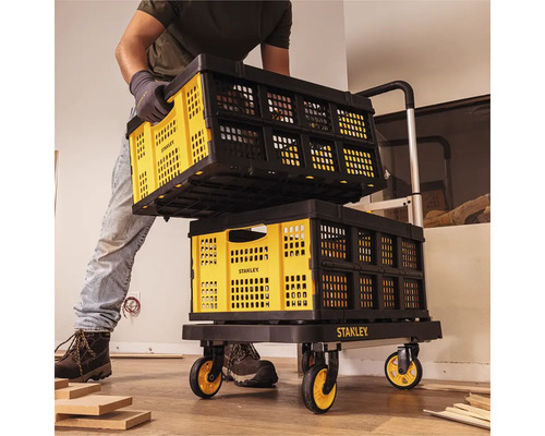 Un homme transporte des caisses de transport pliables Stanley sur un chariot