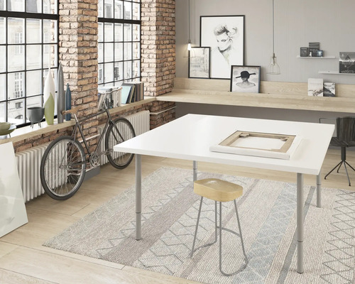 Atelier mit weißem Tisch, Hocker und Teppich vor Ziegelwand