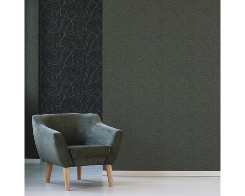 Dekorative Wandgestaltung mit einer einfarbigen Tapete und einer Tapete mit Zweigmuster, kombiniert mit einem Sessel.