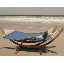 Un homme se détend dans un hamac bleu avec cadre en bois sur la plage