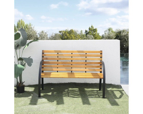 Banc de jardin en lattes de bois et structure métallique noire devant un mur blanc