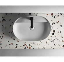 Vue de dessus d''un lavabo à poser ovale avec robinet sur un plan de travail à motif terrazzo.