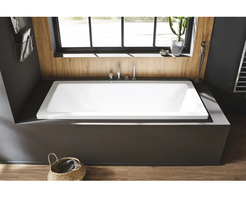 Eingebaute rechteckige Badewanne mit Armaturen und Dekorartikeln im Badezimmer.