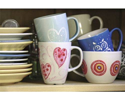 Pile de tasses en céramique avec différents décors et assiettes sur l''étagère.