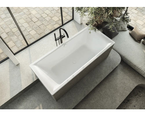 Baignoire îlot dans une salle de bains lumineuse avec fenêtre et coin salon