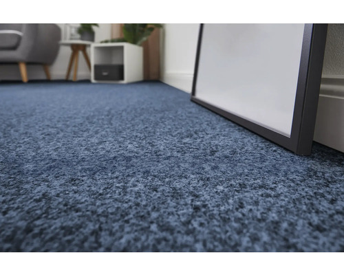 Gros plan d'un revêtement de sol en moquette bleue dans une pièce lumineuse.