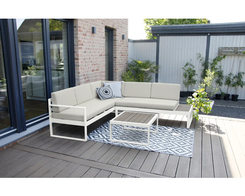 Salon de jardin avec canapé d''angle, table et tapis sur une terrasse