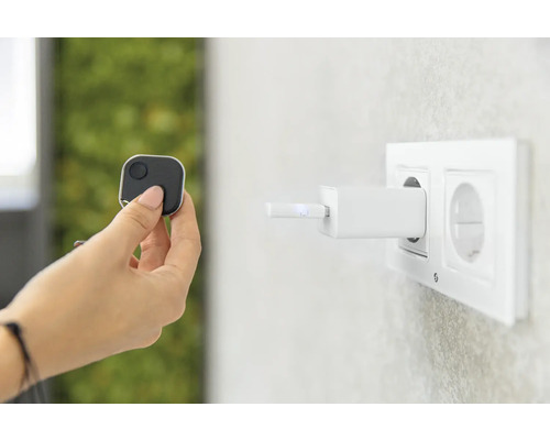 Une main tient un traceur carré, tandis qu''un chargeur est branché sur une prise