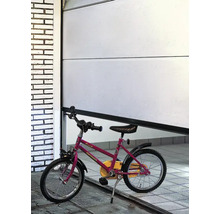 Ein teilweise geöffnetes weißes Garagentor mit einem Kinderfahrrad davor.